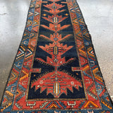 Full view of Persian-style runner rug with navy center panel, rust medallion, and borders