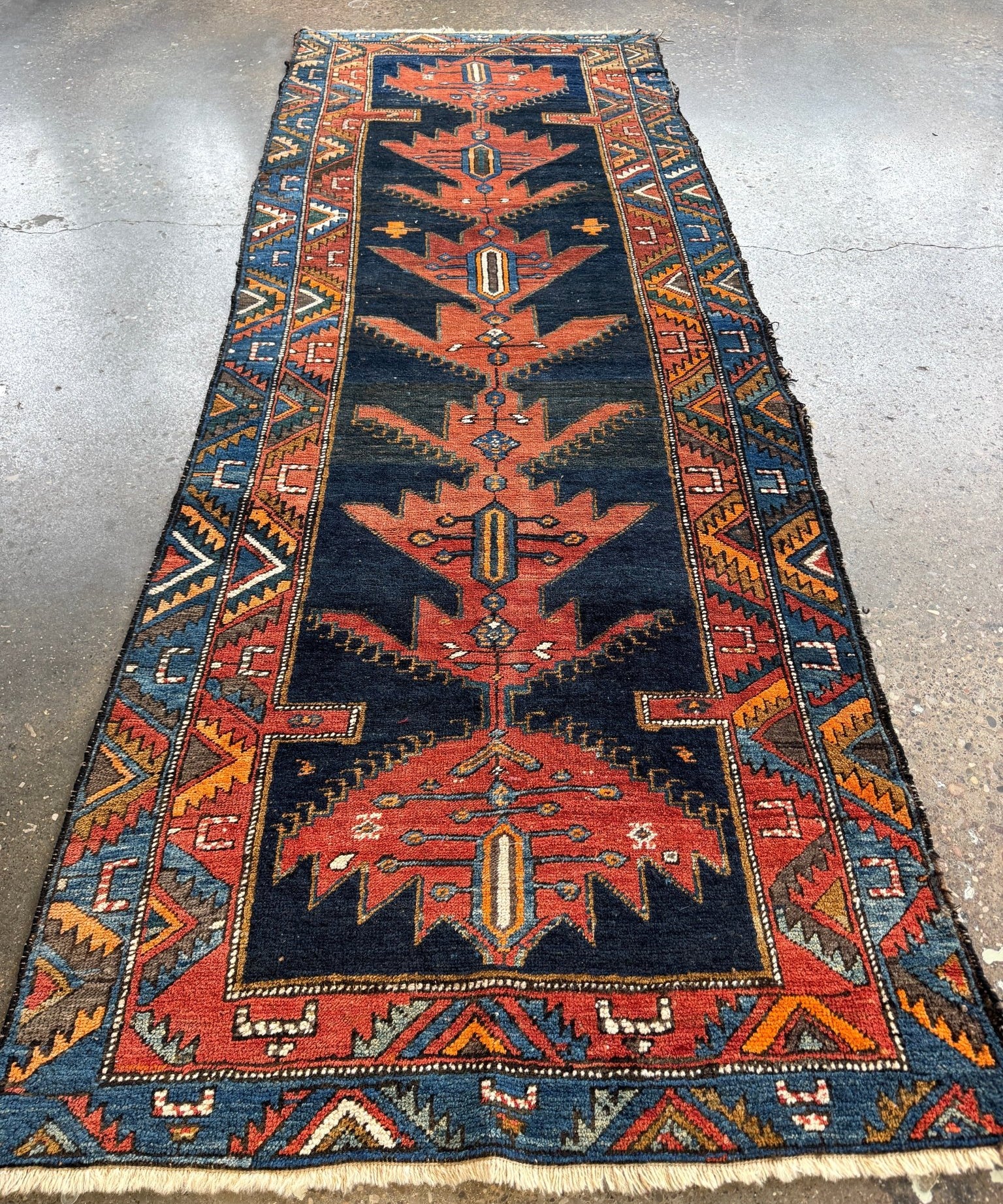 Full view of Persian-style runner rug with navy center panel, rust medallion, and borders