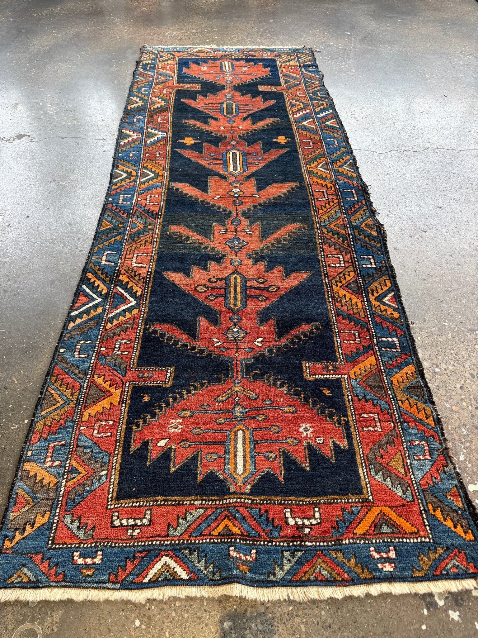 Full view of Persian-style runner rug with navy center panel, rust medallion, and borders