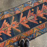Runner rug with navy blue field and rust-orange star and diamond pattern border