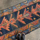 Runner rug with navy blue field and rust-orange star and diamond pattern border