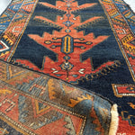 Persian-style runner rug with navy field, rust center medallion, and multicolor borders