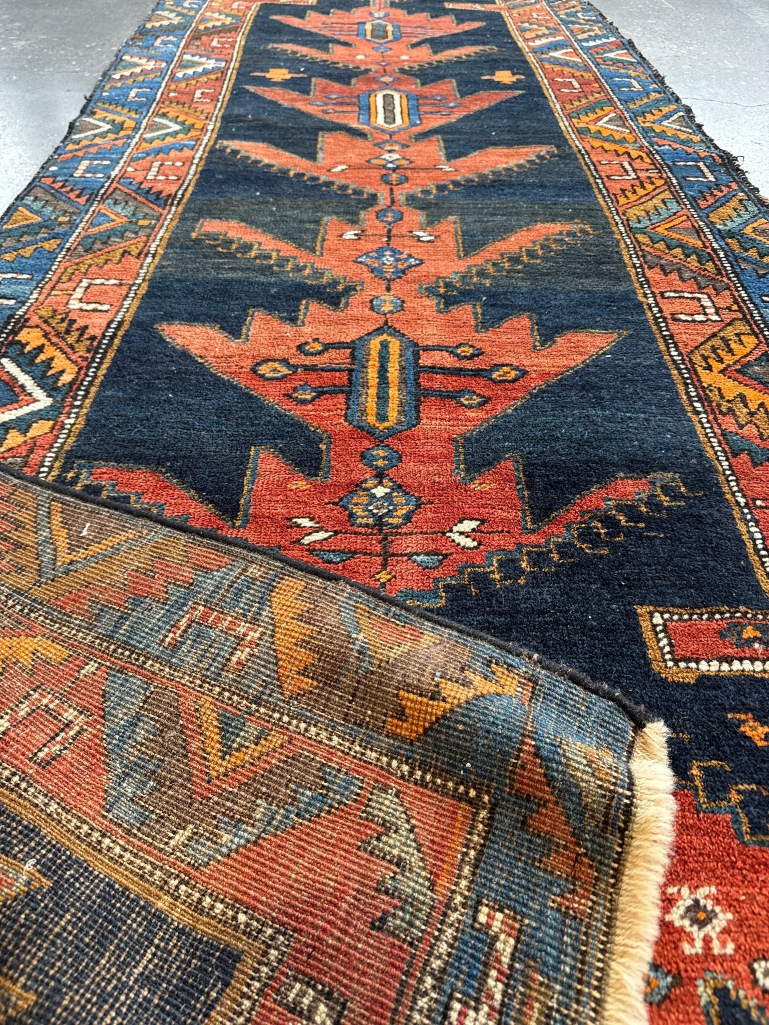Persian-style runner rug with navy field, rust center medallion, and multicolor borders