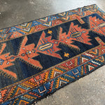Persian runner rug with navy blue and rust geometric medallion motifs, trim border