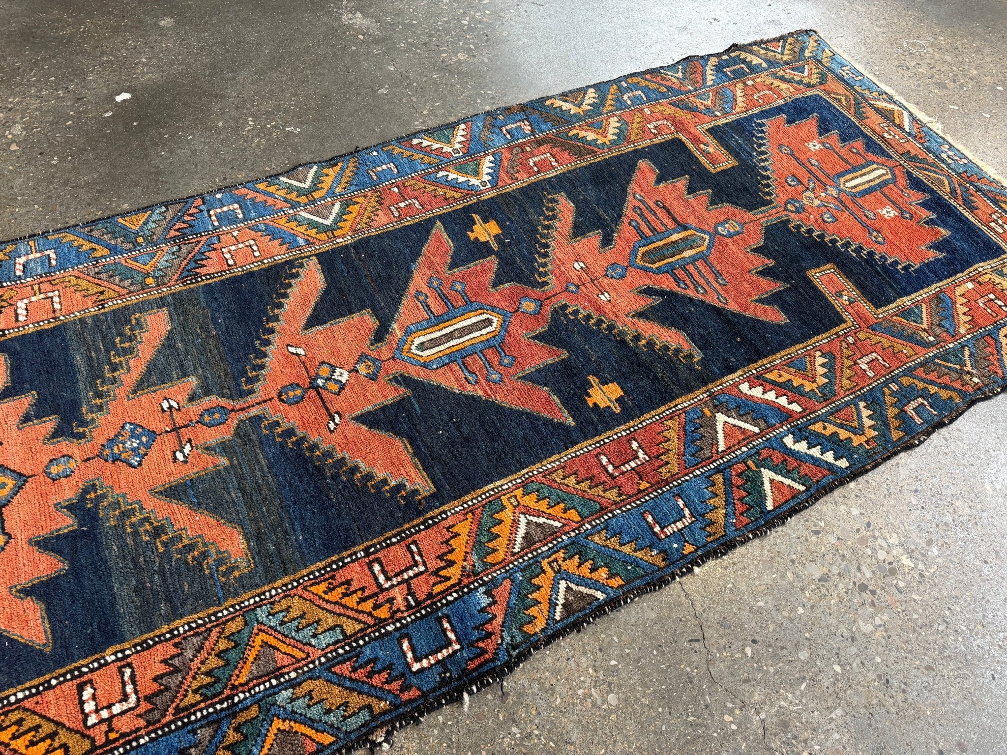 Persian runner rug with navy blue and rust geometric medallion motifs, trim border