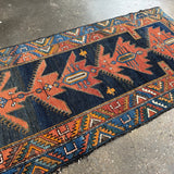 Persian runner rug with navy blue and rust geometric medallion motifs, trim border