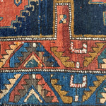 Close-up of Persian runner rug border with red, navy, teal, and cream repeating shapes