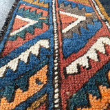 Close-up of Persian runner rug weave with navy, rust, teal, and cream geometric motifs