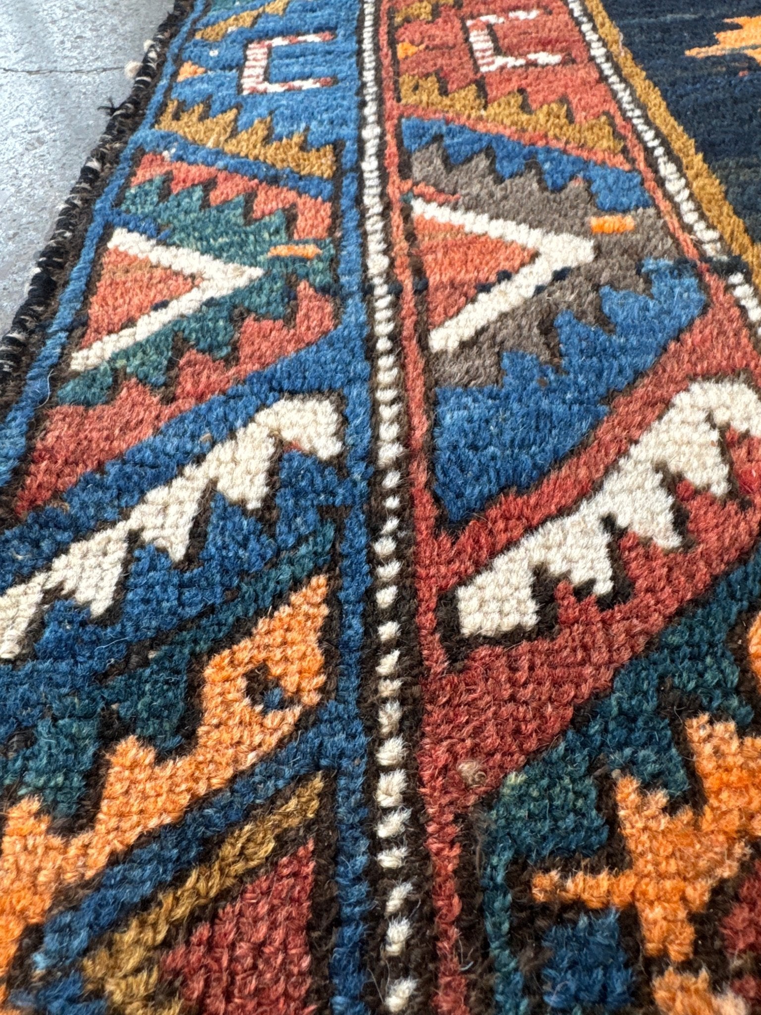 Close-up of Persian runner rug weave with navy, rust, teal, and cream geometric motifs