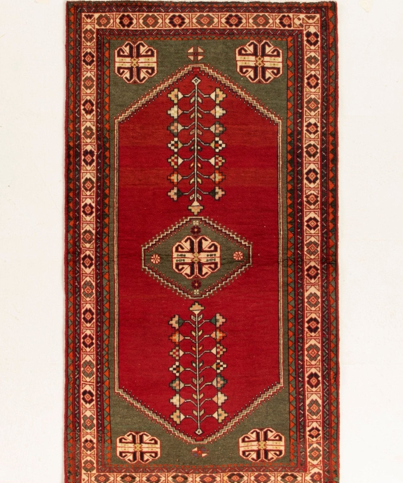 Rectangular Persian-style rug with red field, dark border, and geometric medallion motifs.