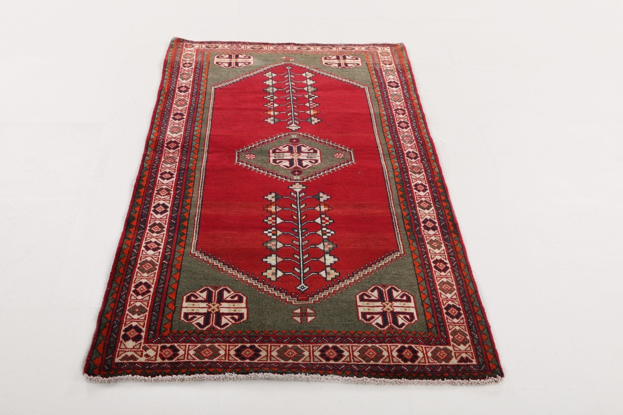 Rectangular Persian-style rug with red center, dark border, and central tree-like motif.