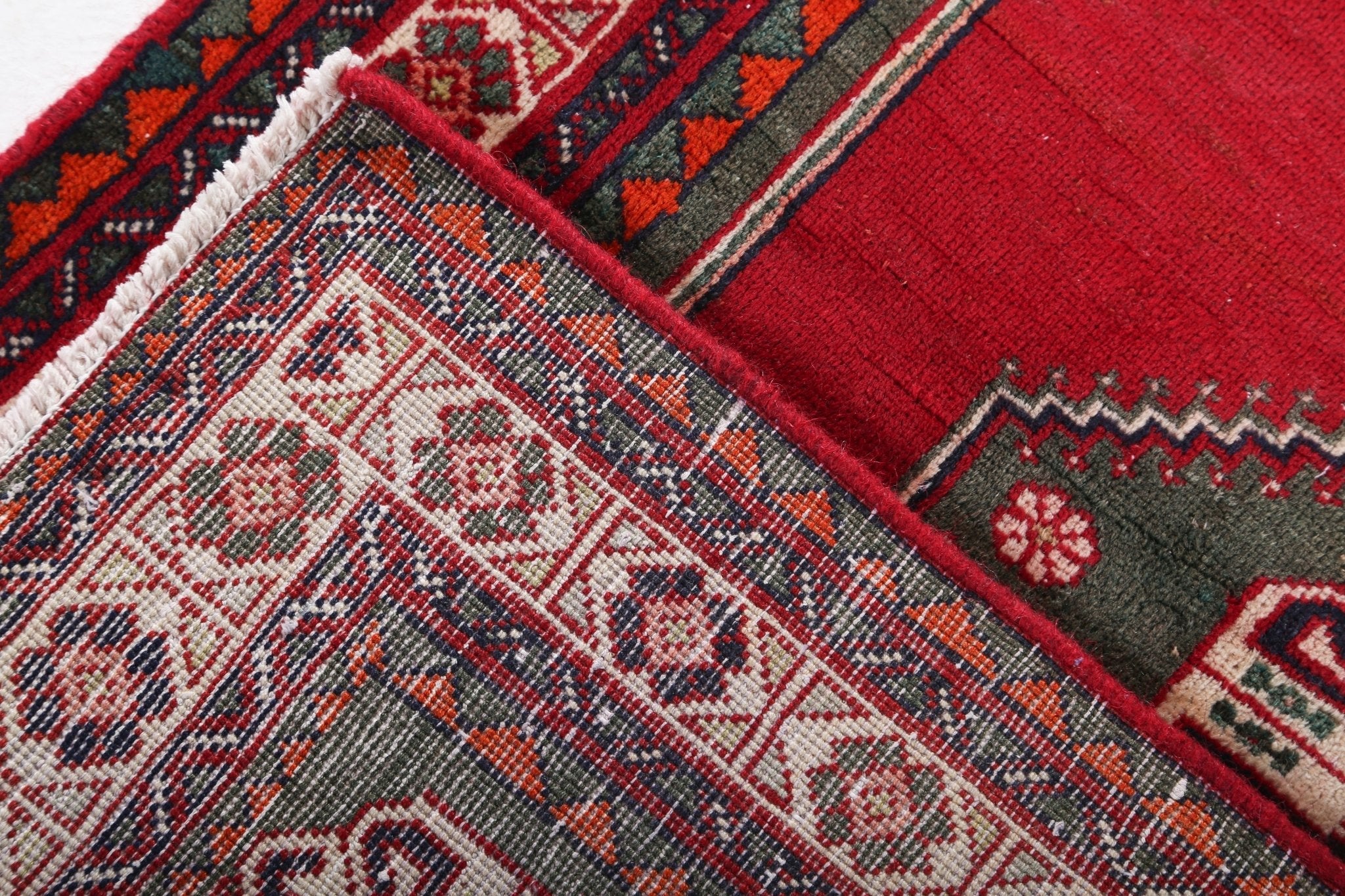 Red Persian-style rug corner with striped border and gray, blue, beige pattern