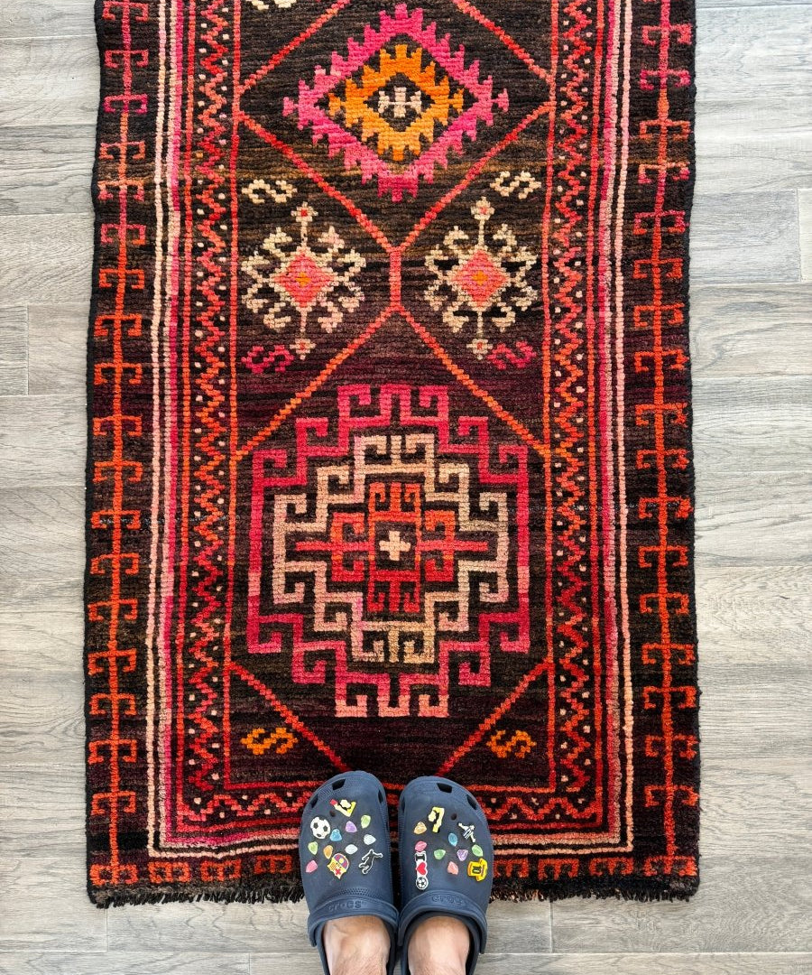 Runner rug with dark navy, red, and cream geometric motifs; fringed border.