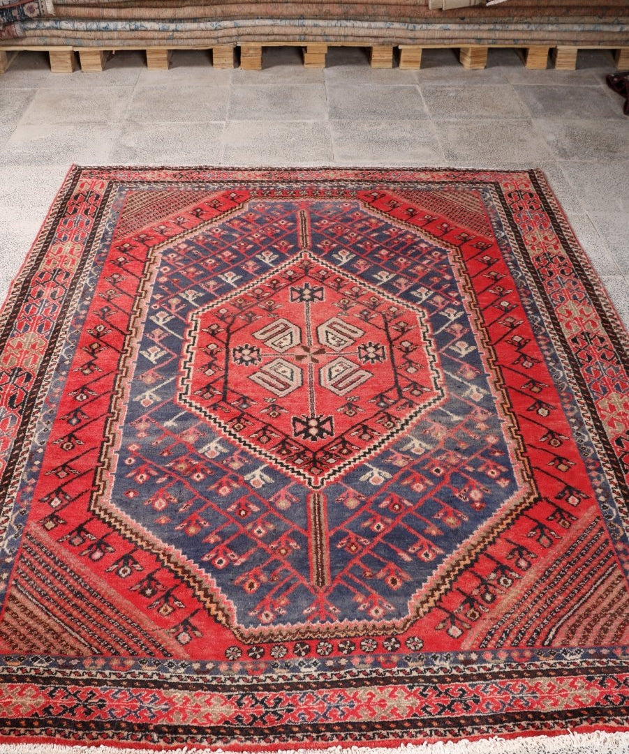 Persian Shahreh-Babak rug on tile floor, red center medallion with blue star pattern