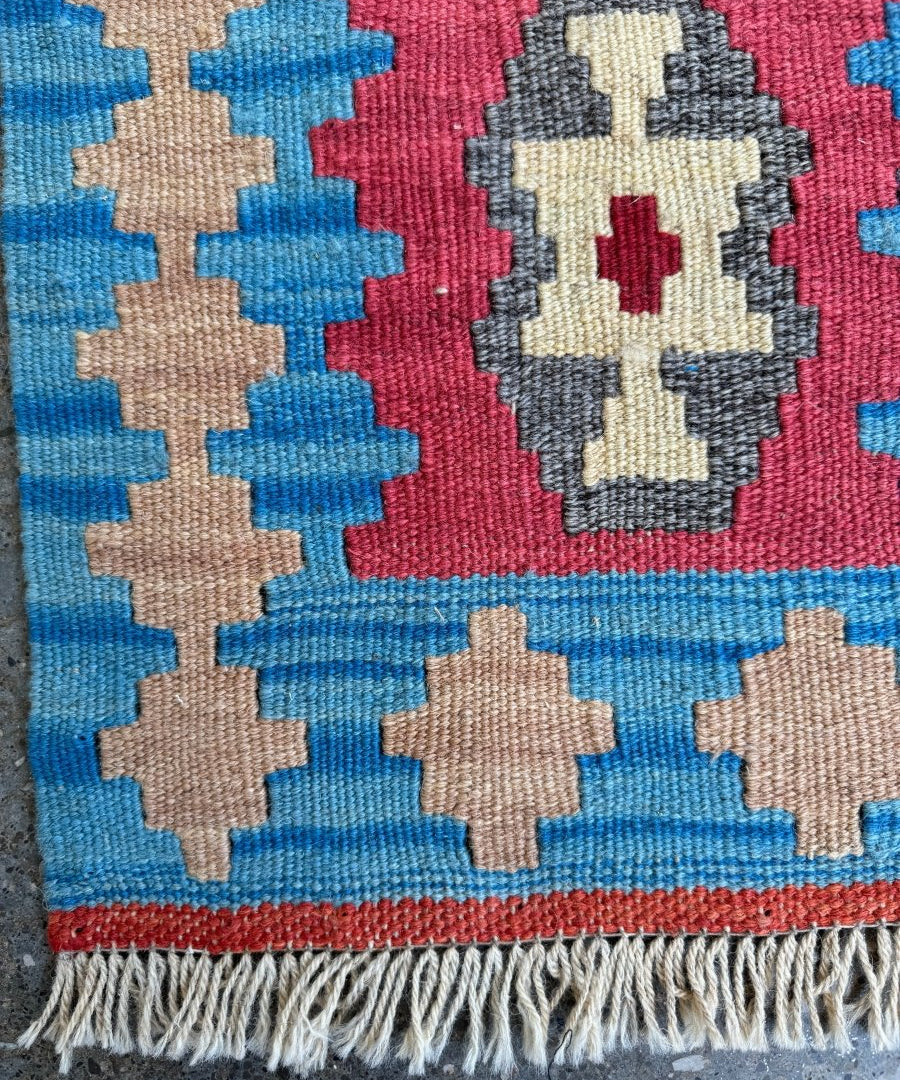 Persian Shiraz kilim rug close-up of red medallion with gray and cream cross shapes