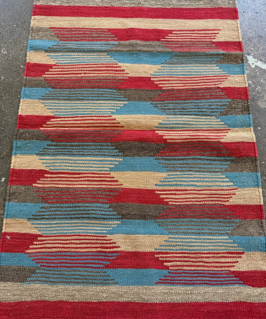 Persian Shiraz kilim rug with red, blue, and beige geometric stripes and fringe ends.