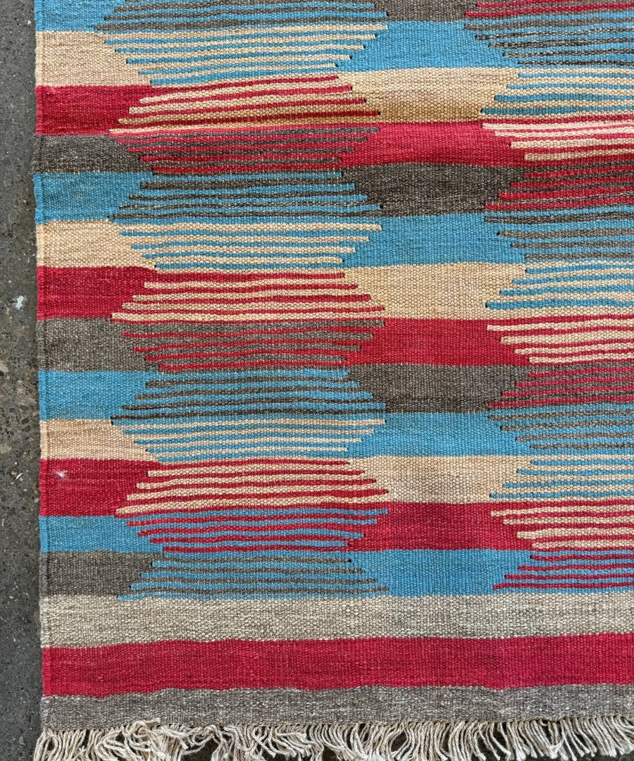 Persian Shiraz kilim rug, close view of fringe and multicolor geometric pattern.