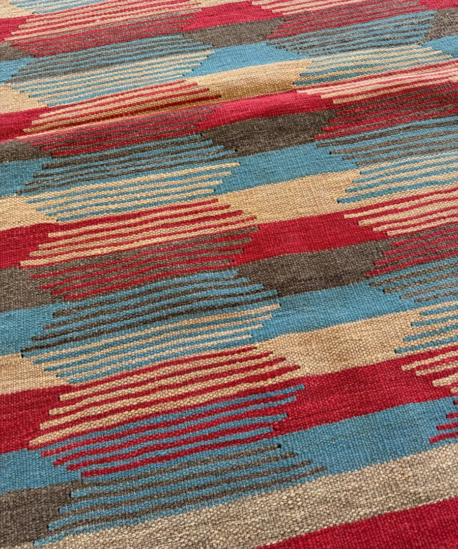 Persian Shiraz kilim rug section with red, blue, gray, and beige horizontal motifs.