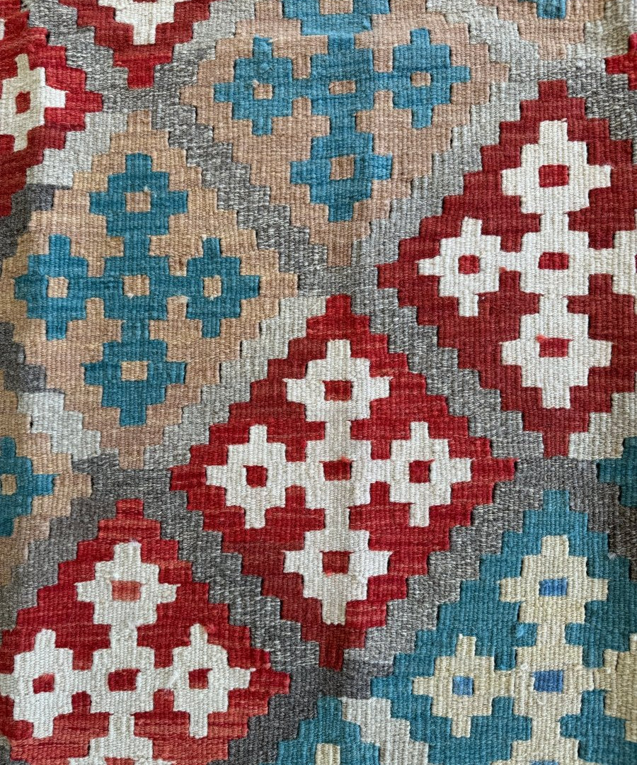 Kilim rug close-up of red, blue, cream cross motifs and zigzag borders