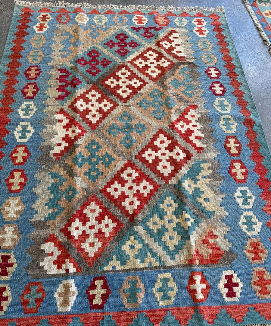 Kilim rug with central diamond medallion in red, blue, and cream, fringed edge