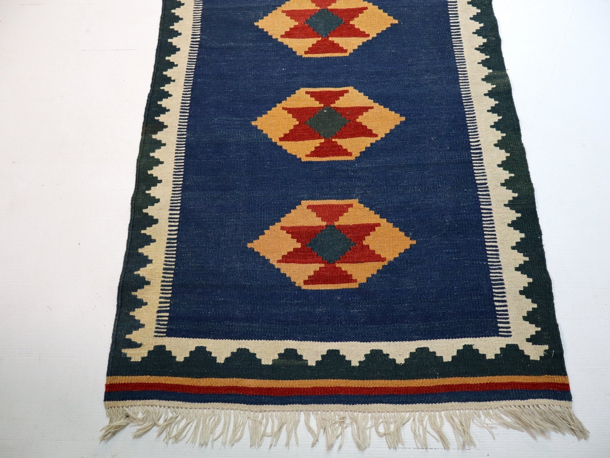 Blue kilim runner footer with diamond motifs, cream border and multicolor stripe edge
