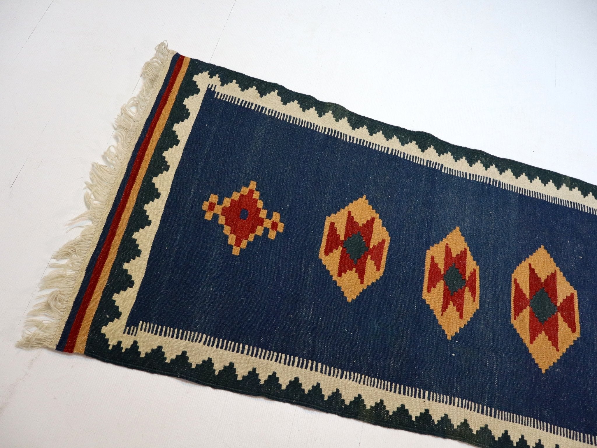 Blue kilim runner with orange and cream diamond motifs, fringed end and border