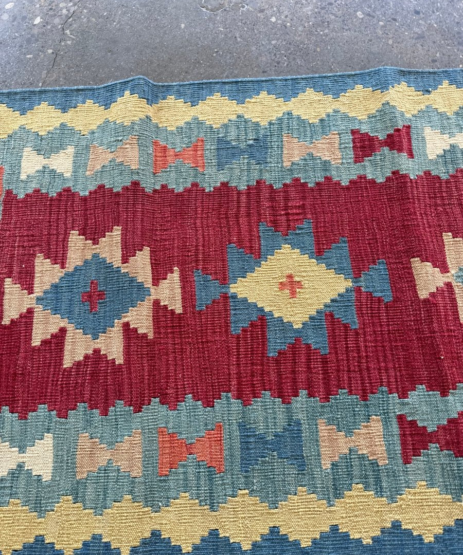 Kilim runner rug border detail with repeating cross and chevron motifs in red and blue