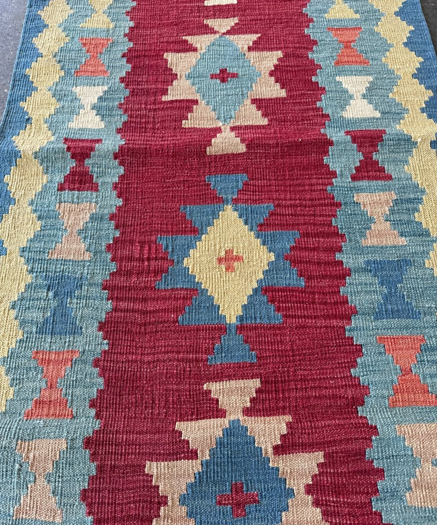 Kilim runner rug close-up with zigzag and diamond motifs in burgundy, blue, and cream
