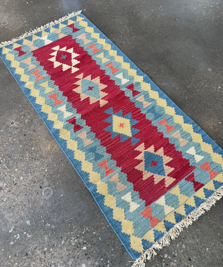Kilim runner rug with geometric pattern in blue, burgundy, cream, and yellow