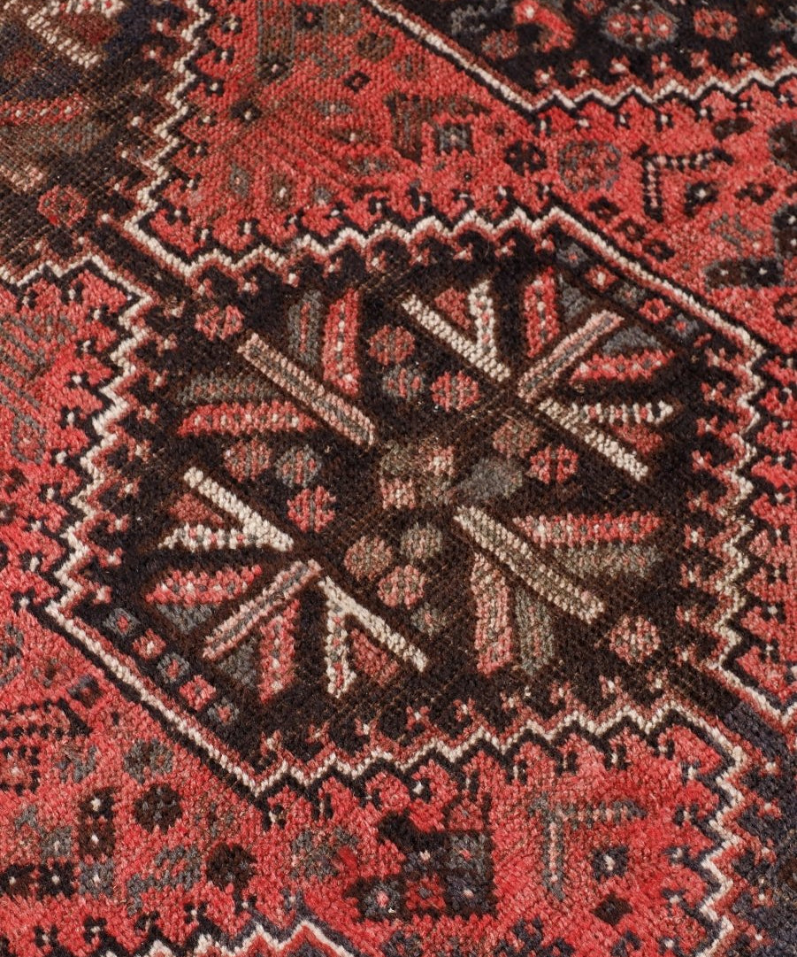 Persian Shiraz rug close-up showing red, black, and gray diamond pattern border