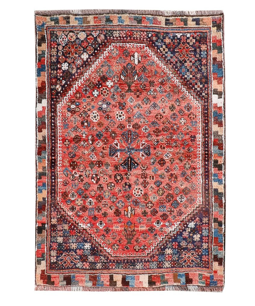 Persian-style rug with red medallion center, blue accents, and geometric border in dark tones