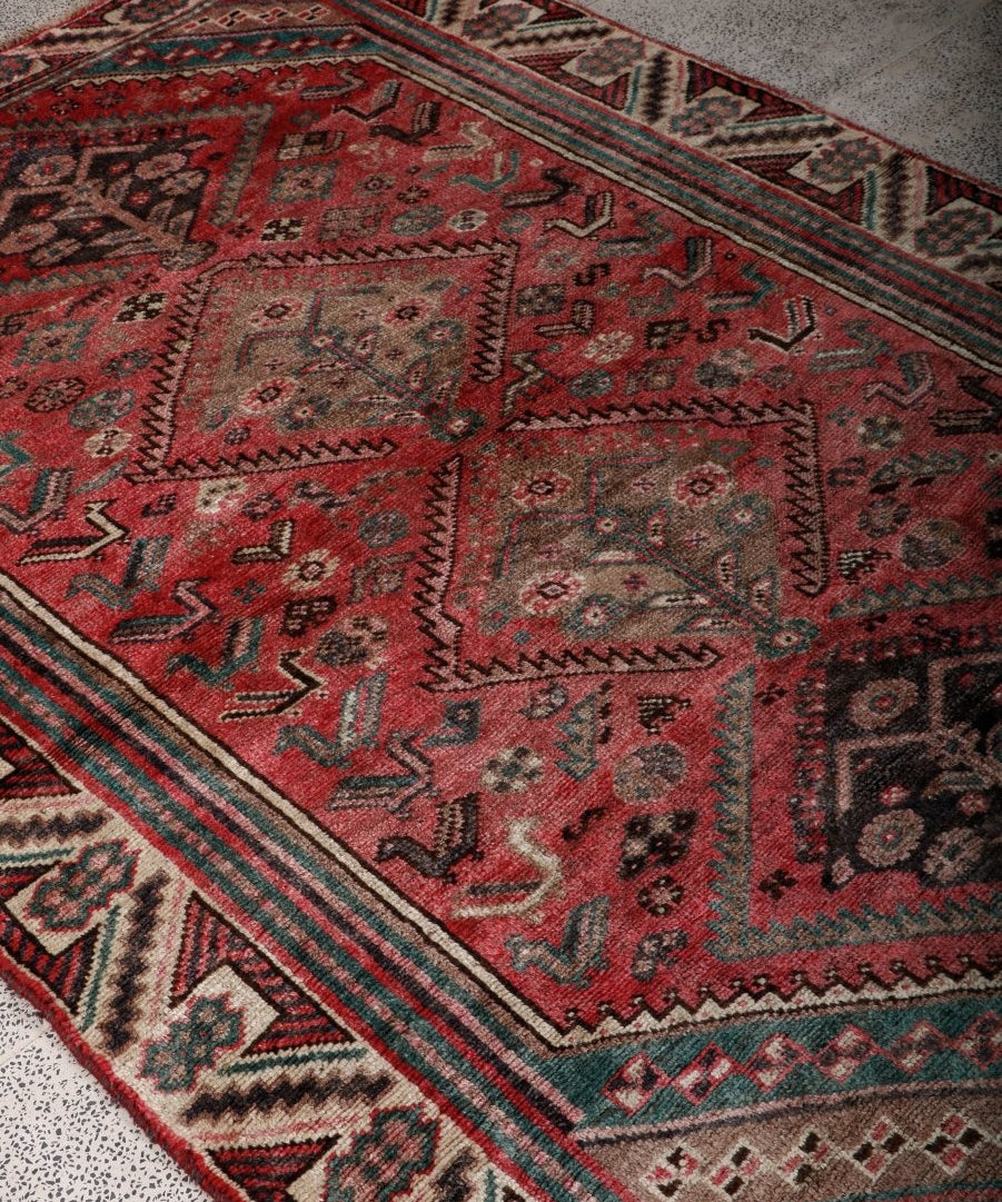 Persian Shiraz rug detail, red with teal stripes and cream geometric medallion motifs.