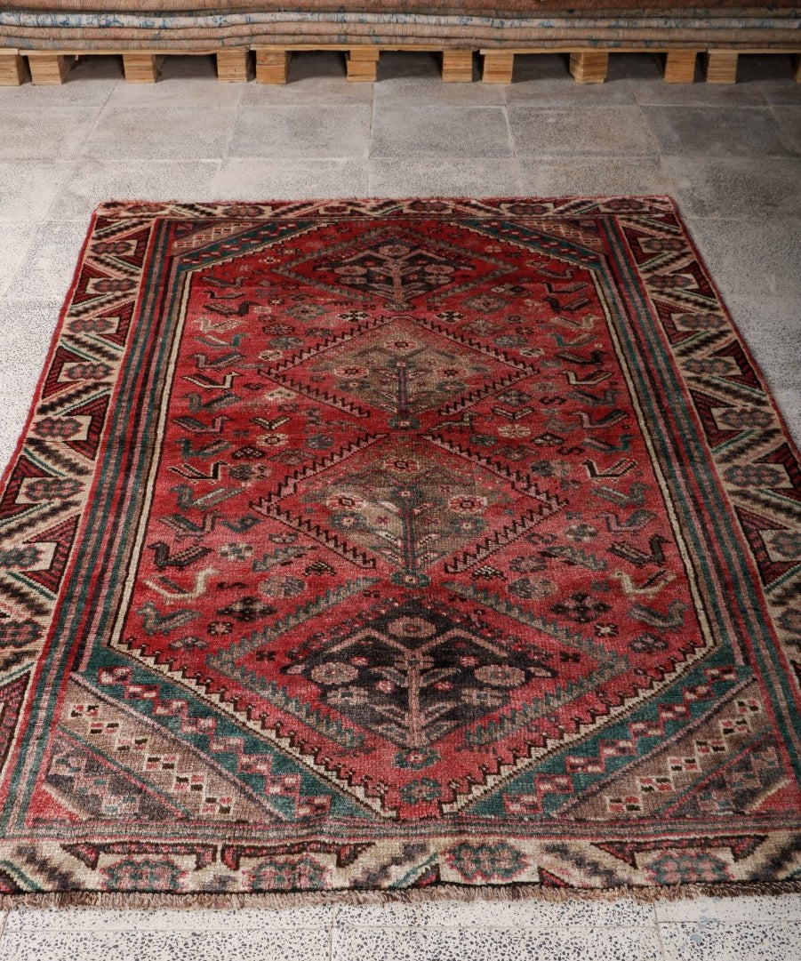 Persian Shiraz rug, red and dark accents with geometric border and medallion pattern.