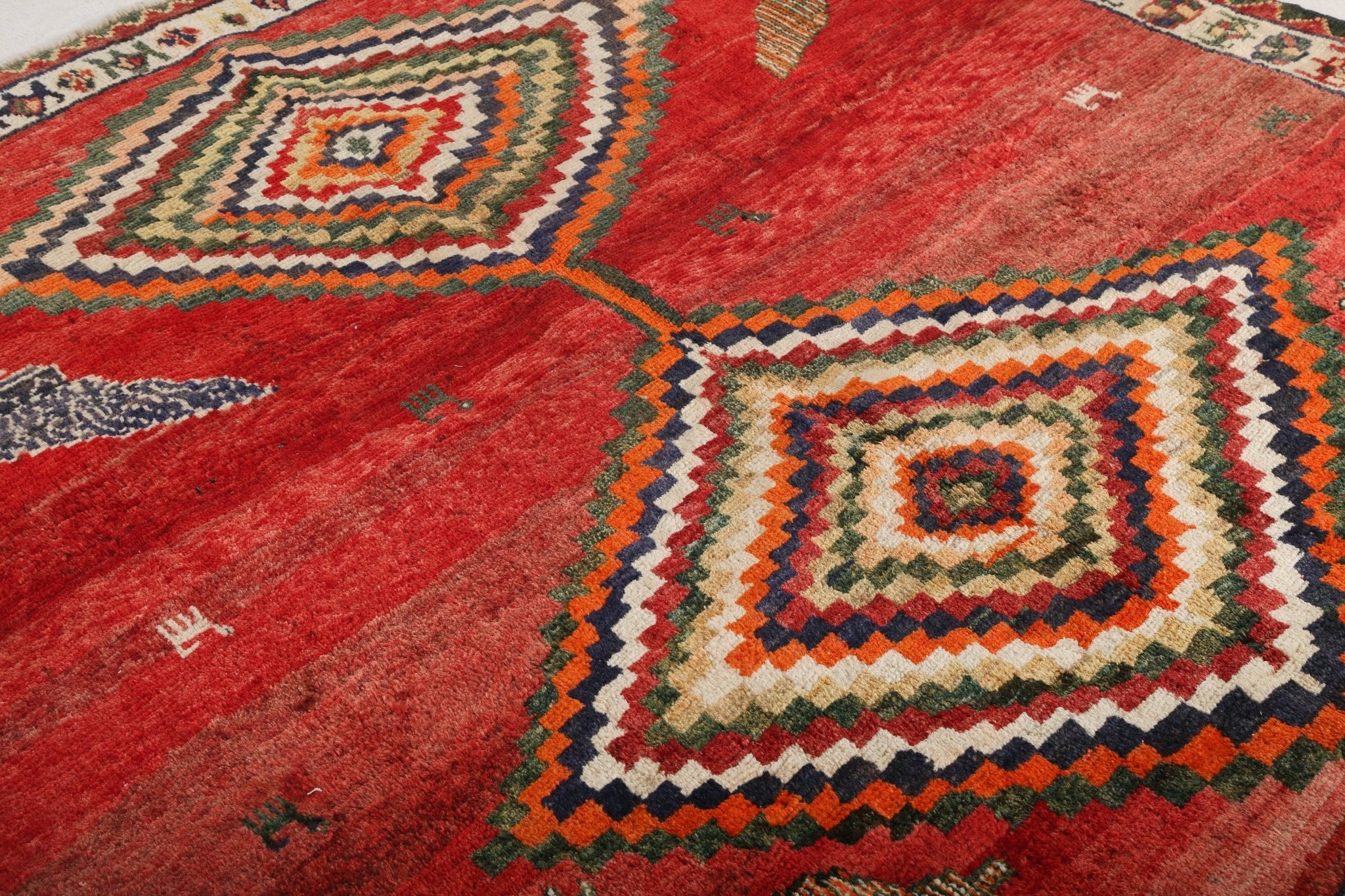 Persian Shiraz rug: red field with central diamond medallion and zigzag border
