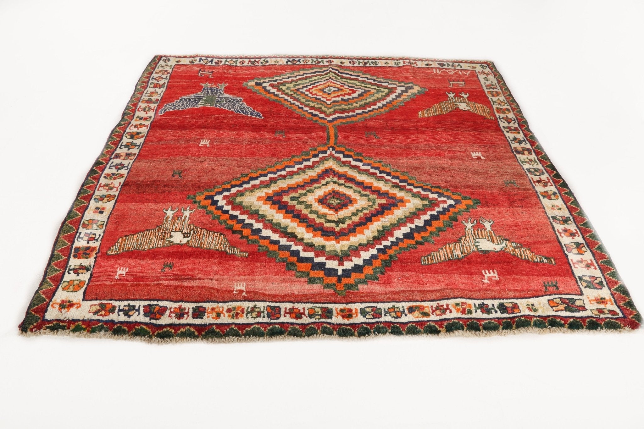 Red Persian-style rug with central diamond medallion and symmetrical border motifs.