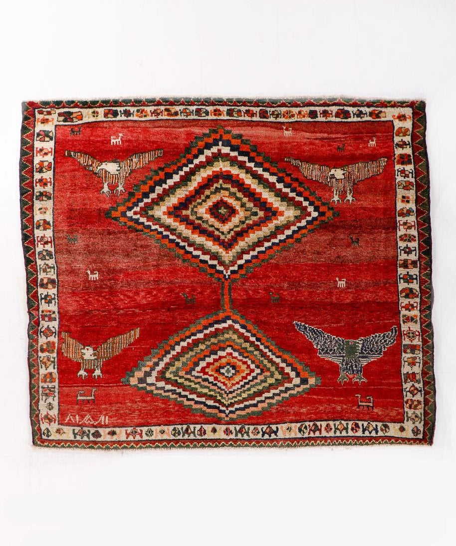 Red Persian-style rug with diamond medallion, birds, and multicolor border design.