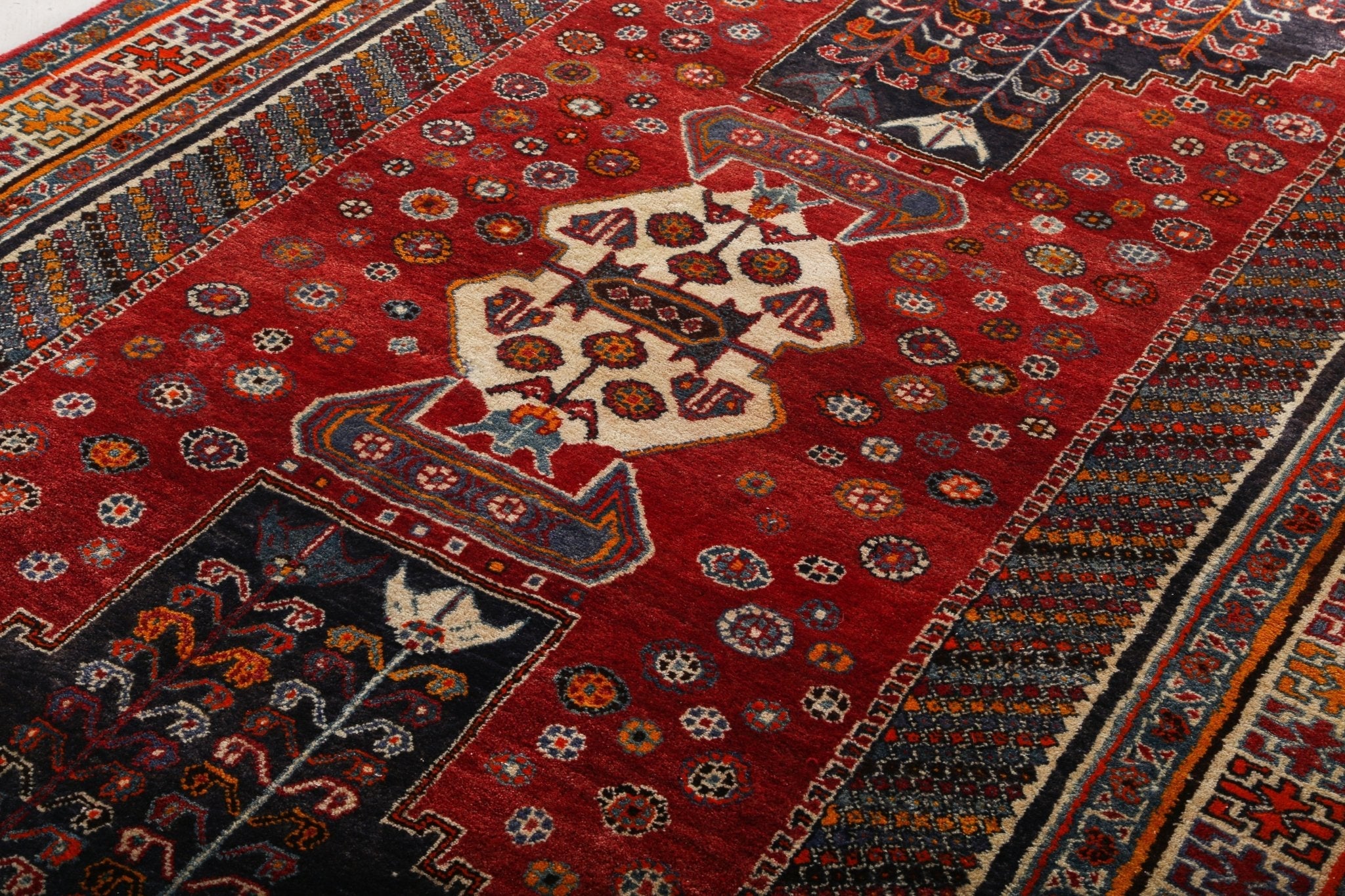 Persian-style red rug with central medallion and geometric border, detailed motifs