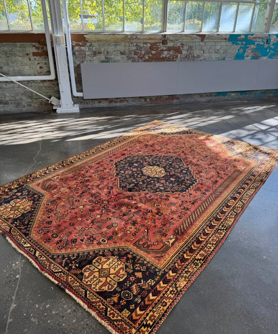 Persian-style area rug with red-pink center medallion, dark navy corner panels