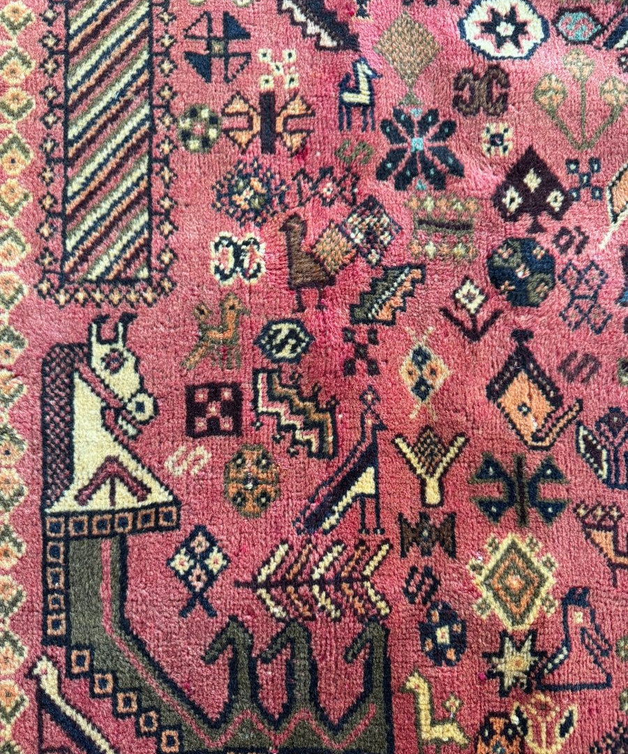 Persian-style rug close-up of red-pink patterned motifs with multicolor geometric accents