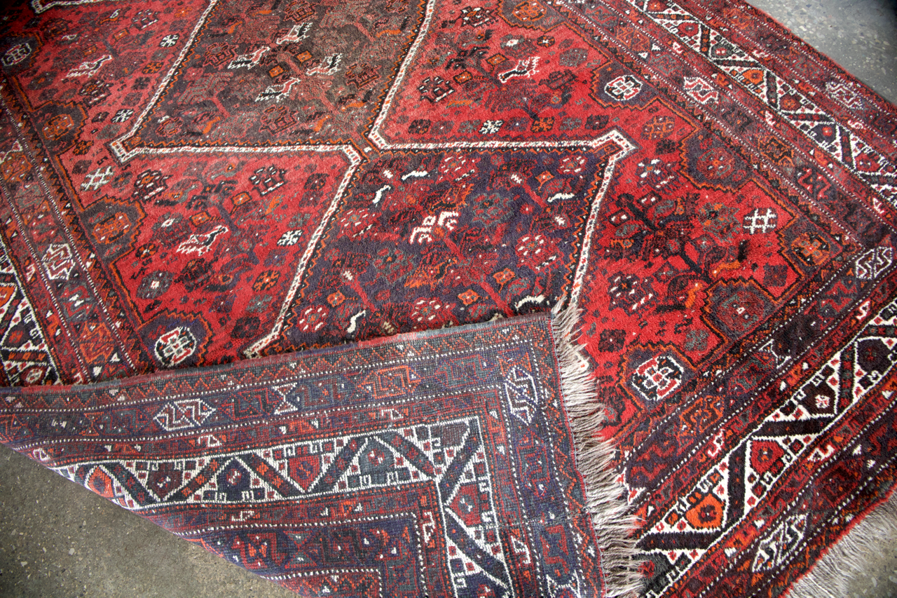 Persian Shiraz rug corner in deep red with navy and ivory geometric pattern and fringe