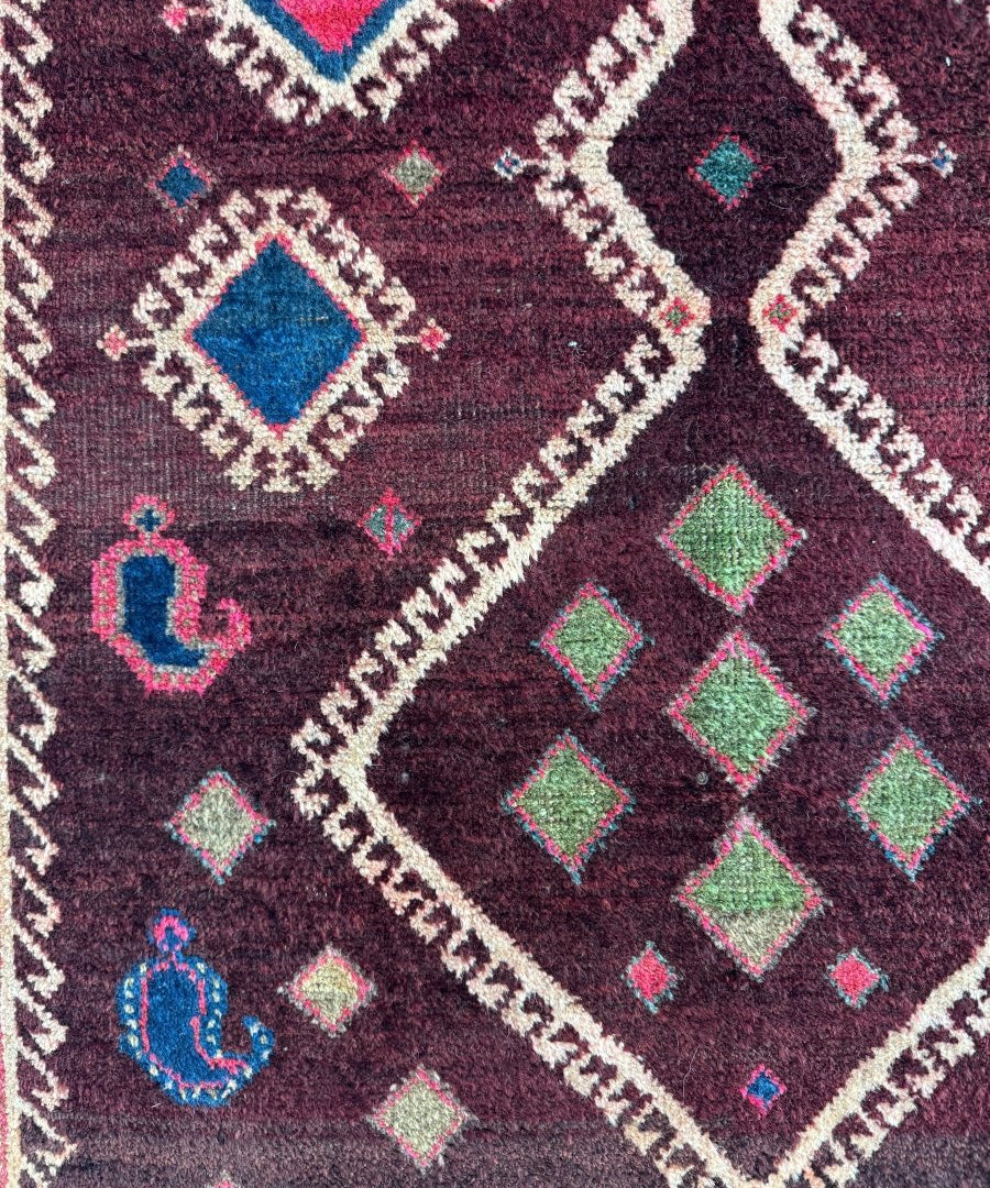 Close-up rug section: dark burgundy with white zigzag, blue and green diamond shapes.