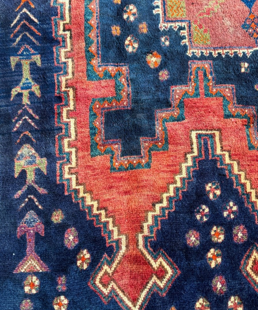 Persian Sirjan rug close-up of navy blue and red star medallion with diamond motifs