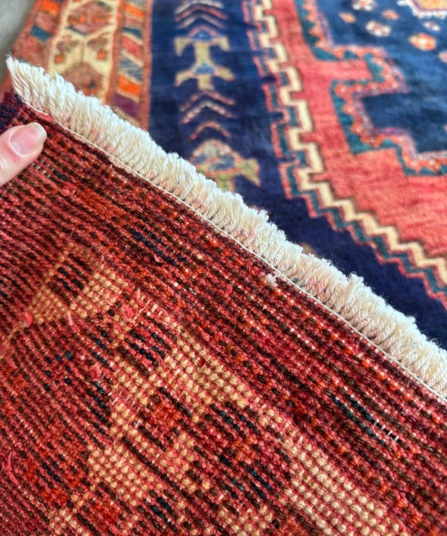 Persian Sirjan rug corner detail with textured weave and cream fringe on red border