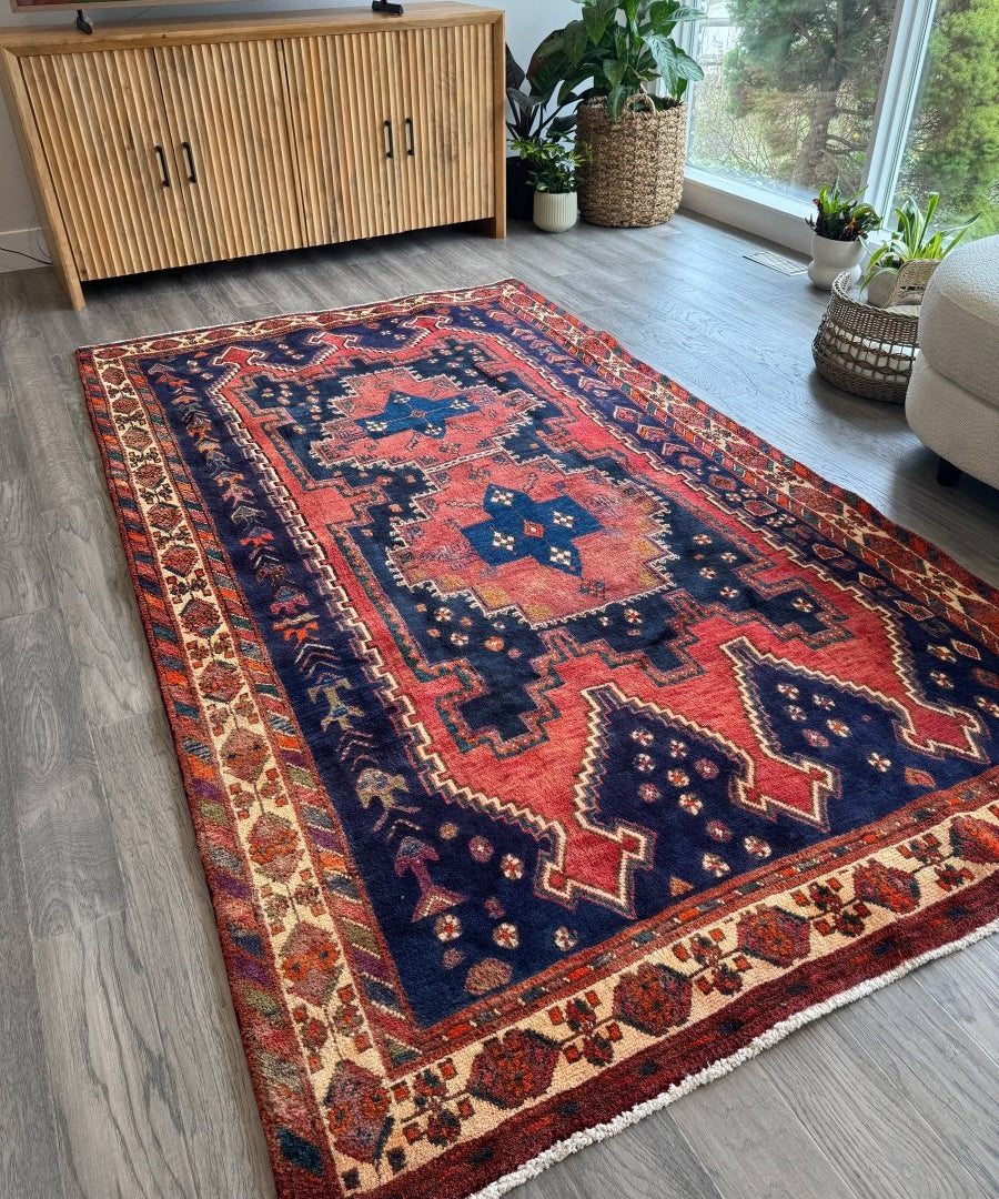 Persian Sirjan rug with navy blue field, red medallion, and cream bordered pattern