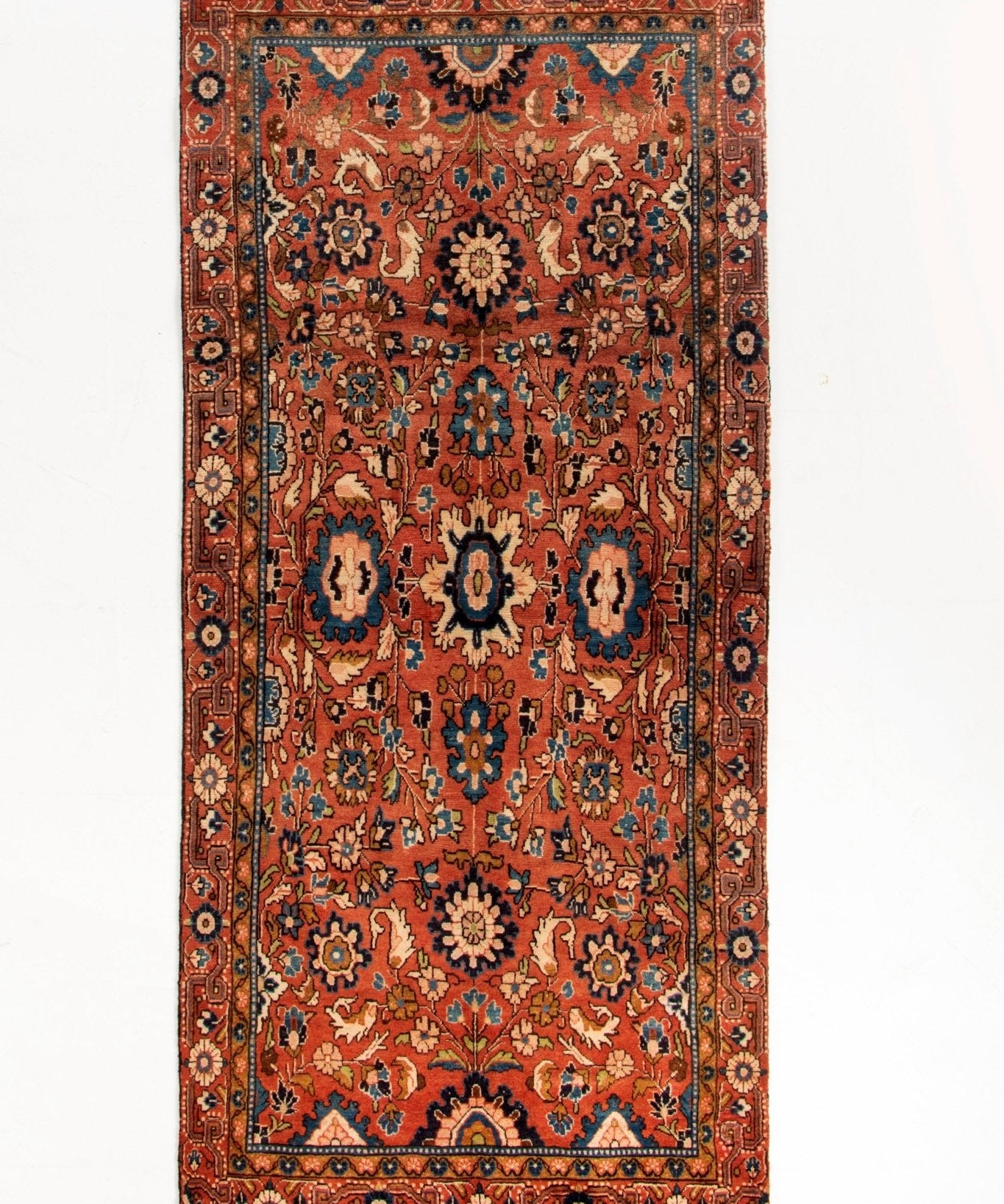 Runner rug full view with red ground, central medallions, and geometric borders