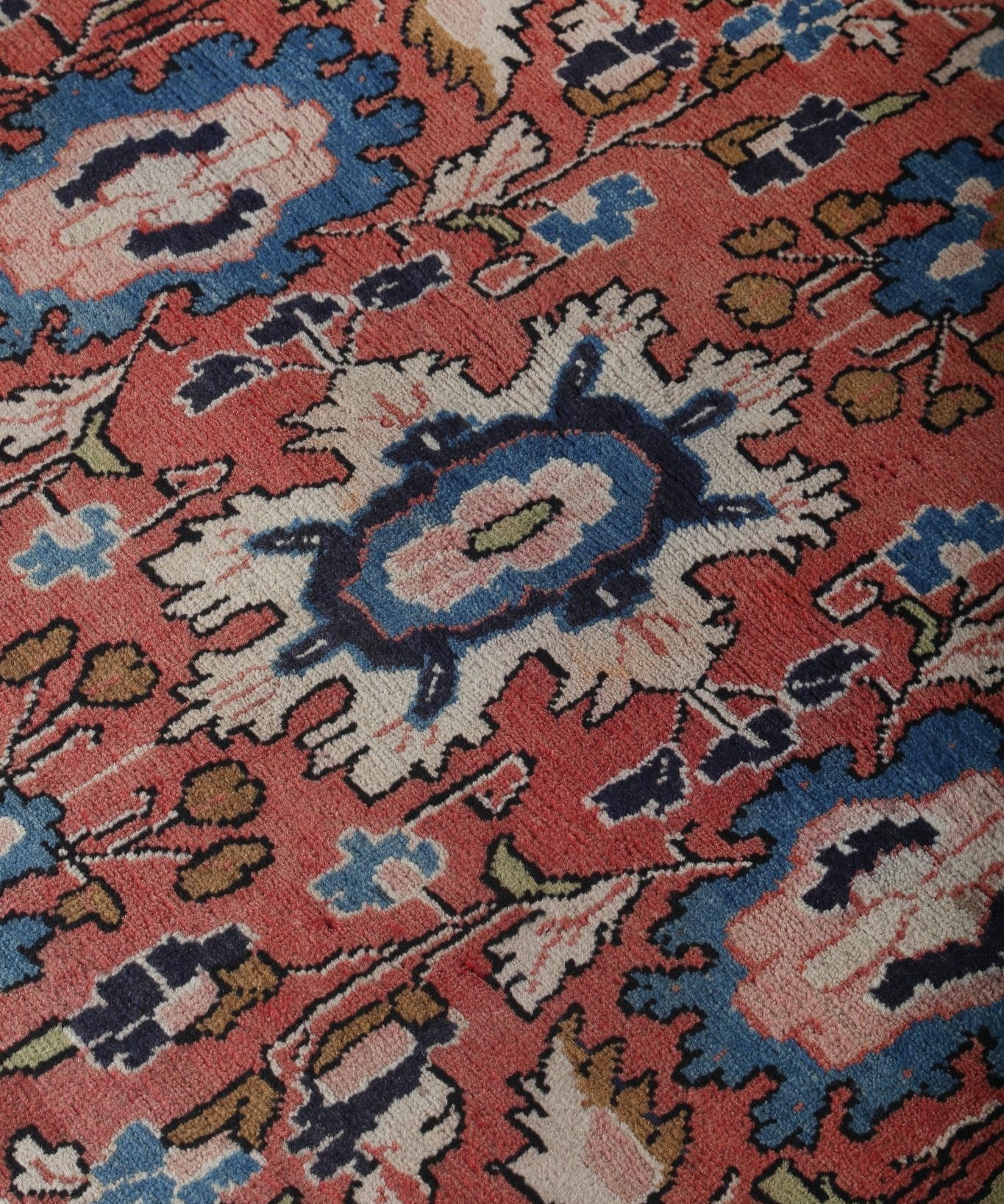 Persian-style runner rug surface close-up with rust red and blue floral tile design