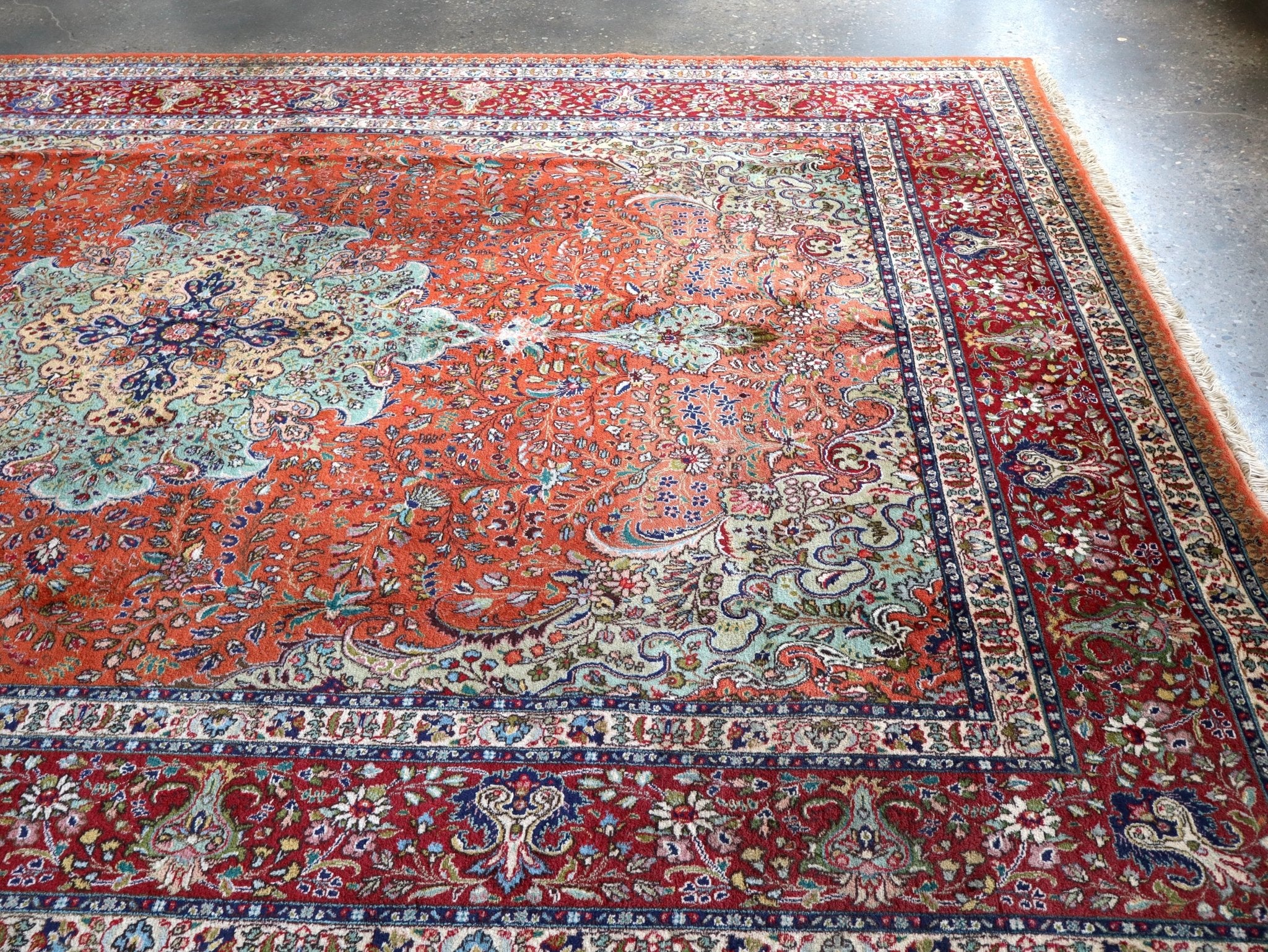 Persian rug laid flat with red-orange center, cream rosette motifs, and patterned border.