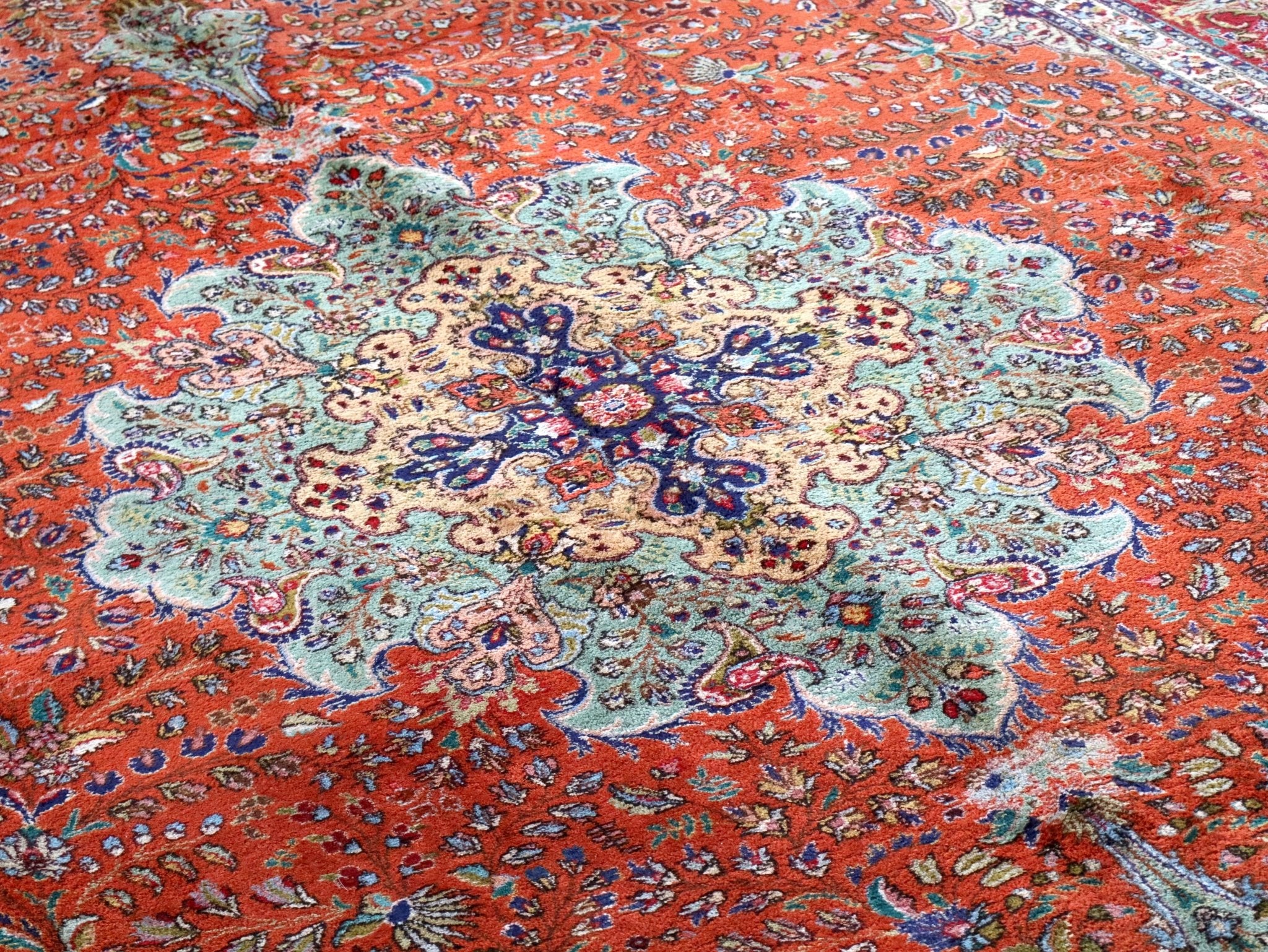 Persian rug with red-orange field and ornate central medallion in cream, blue, and teal.