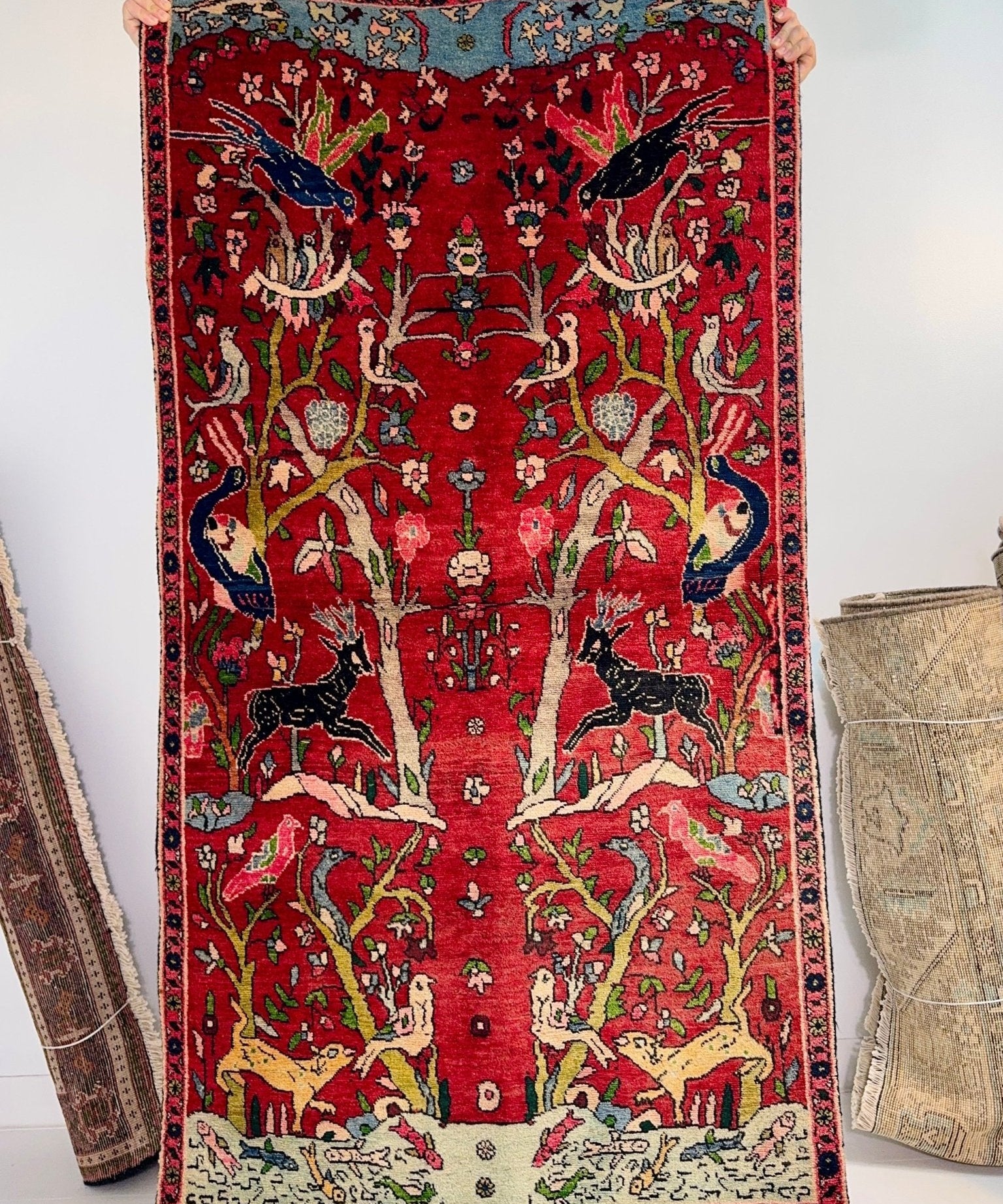 Red Persian Tabriz-style rug featuring central tree motif, birds, and multicolor detail.