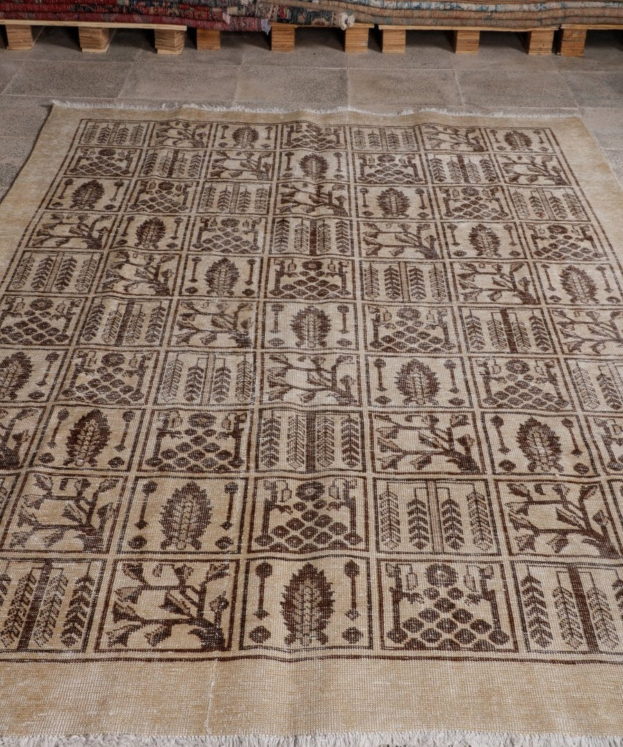 Persian Tabriz rug with repeating dark brown motifs on beige field, fringed edges.